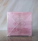 A pink rectangular box with diagonal crisscross fold lines, photographed on a light marble-like surface against a pale background.