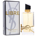 Yves Saint Laurent Libre Eau de Parfum bottle with its retail box. The clear rectangular bottle contains pale golden-yellow liquid and features a gold-tone decorative ring and YSL logo on the front, next to its white and gray box with gold 'LIBRE' lettering.