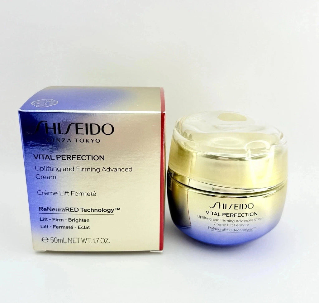 Shiseido Vital Perfection Uplifting and Firming Advanced Cream in a blue-to-gold jar next to its matching blue and gold box, on a white background.