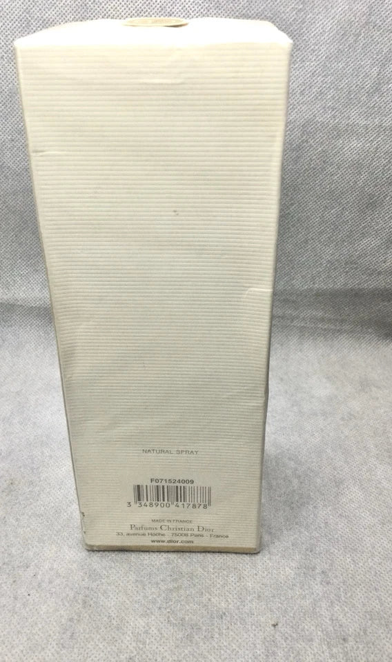 A tall, narrow cream-colored cardboard box with a ribbed texture, standing upright against a gray textured fabric background. The bottom of the box features a barcode and small printed text.