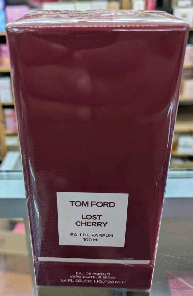 A 100 ml box of Tom Ford Lost Cherry Eau de Parfum, wrapped in clear plastic and featuring a white label on a dark red background.