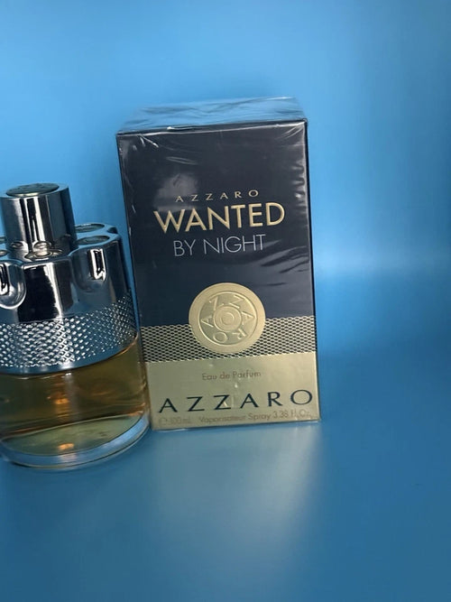A bottle and box of Azzaro Wanted By Night Eau de Parfum on a blue background.