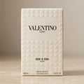A rectangular box of Valentino Uomo Born in Roma Ivory Eau de Toilette, featuring a textured geometric diamond pattern in off-white on a neutral beige background.