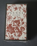 Gucci Bloom Eau de Parfum 100ml spray box, featuring a cream background with a terracotta red floral and butterfly pattern, and black lettering.
