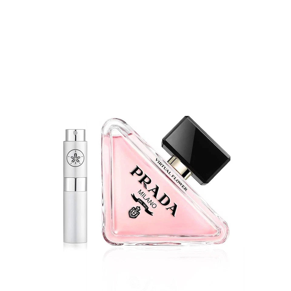 Prada Virtual Flower Eau de Parfum bottle in a triangular clear glass container filled with pink liquid, shown next to a silver cylindrical atomizer vial on a white background.
