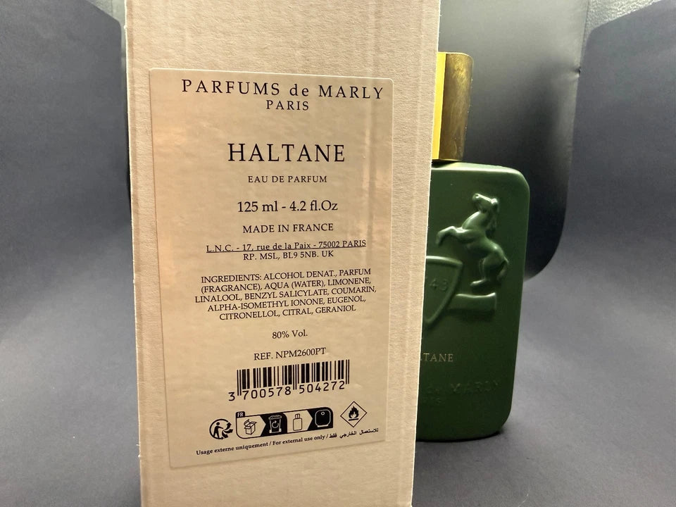 A bottle of Parfums de Marly Halthane Eau de Parfum in a dark green bottle with a gold cap, standing next to its beige cardboard packaging box.