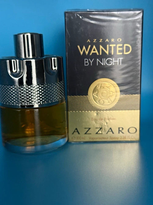 Azzaro Wanted By Night Eau de Parfum bottle with its retail box, both wrapped in protective plastic, set against a solid blue background.